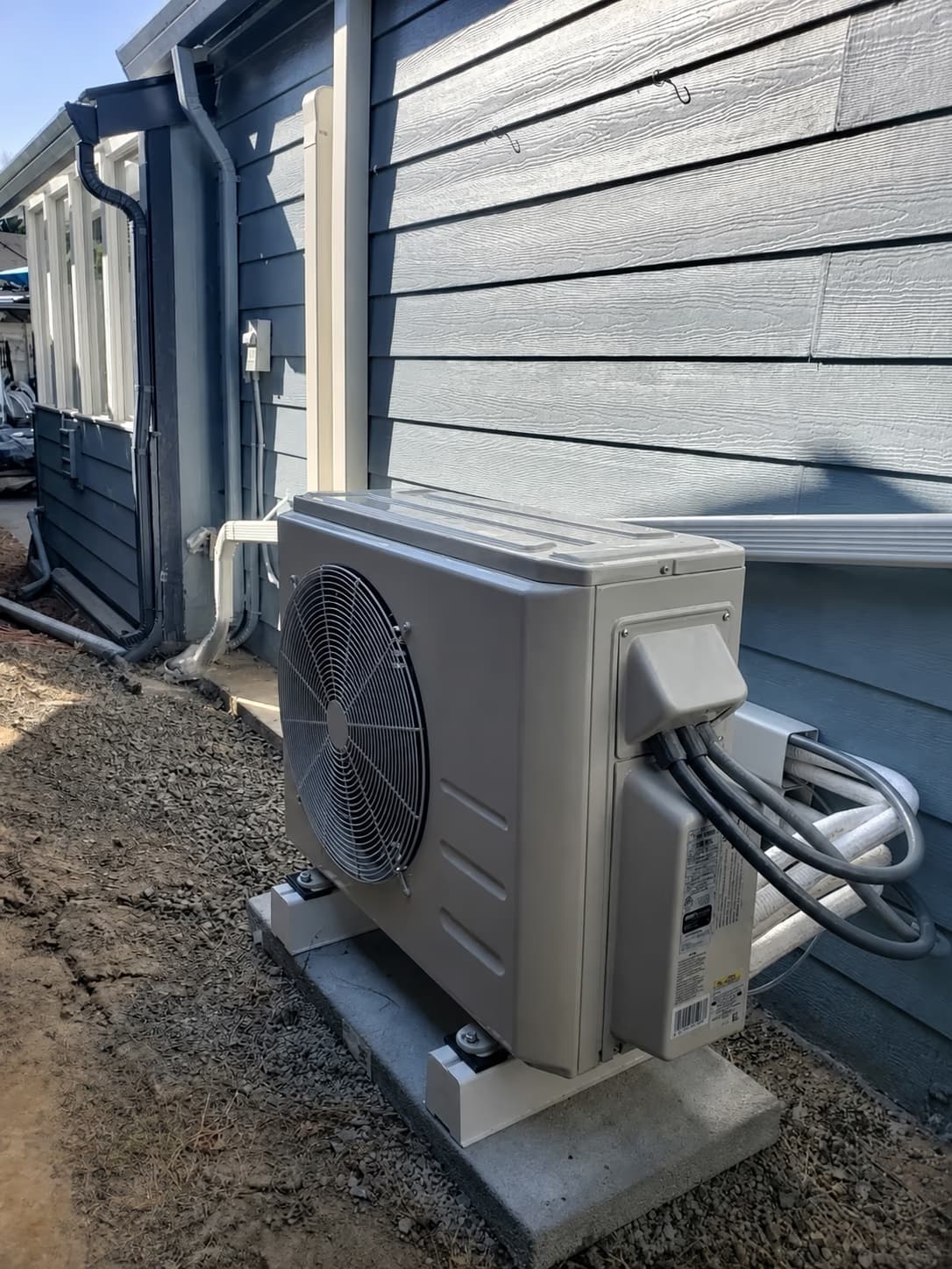 Outdoor heat pump condenser with insulated refrigerant lines installed beside a home