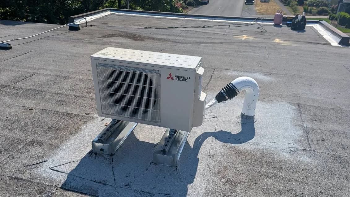 Ductless outdoor unit mounted on equipment rails on a flat roof